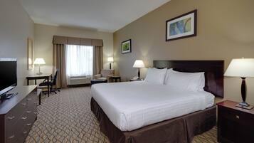 A hotel room with a large bed, a desk with a chair, a television, and two bedside lamps.