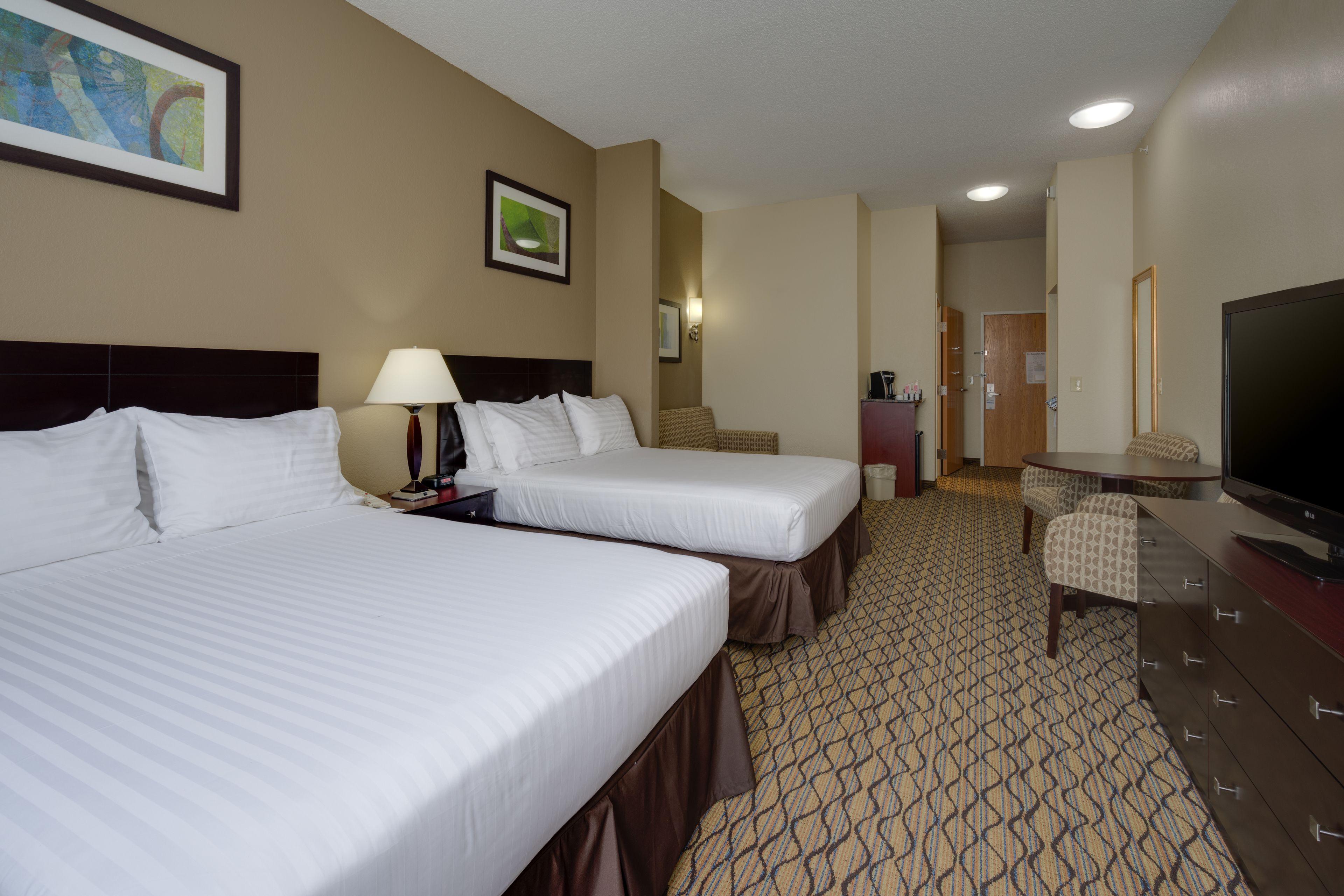 Habitación de hotel con dos camas, televisión, escritorio y silla.