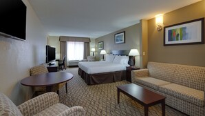 A hotel room with a bed, two bedside tables, a desk with a chair, a sofa, a small table, and a TV. - Holiday Inn Express Charles Town by IHG (Charles Town)