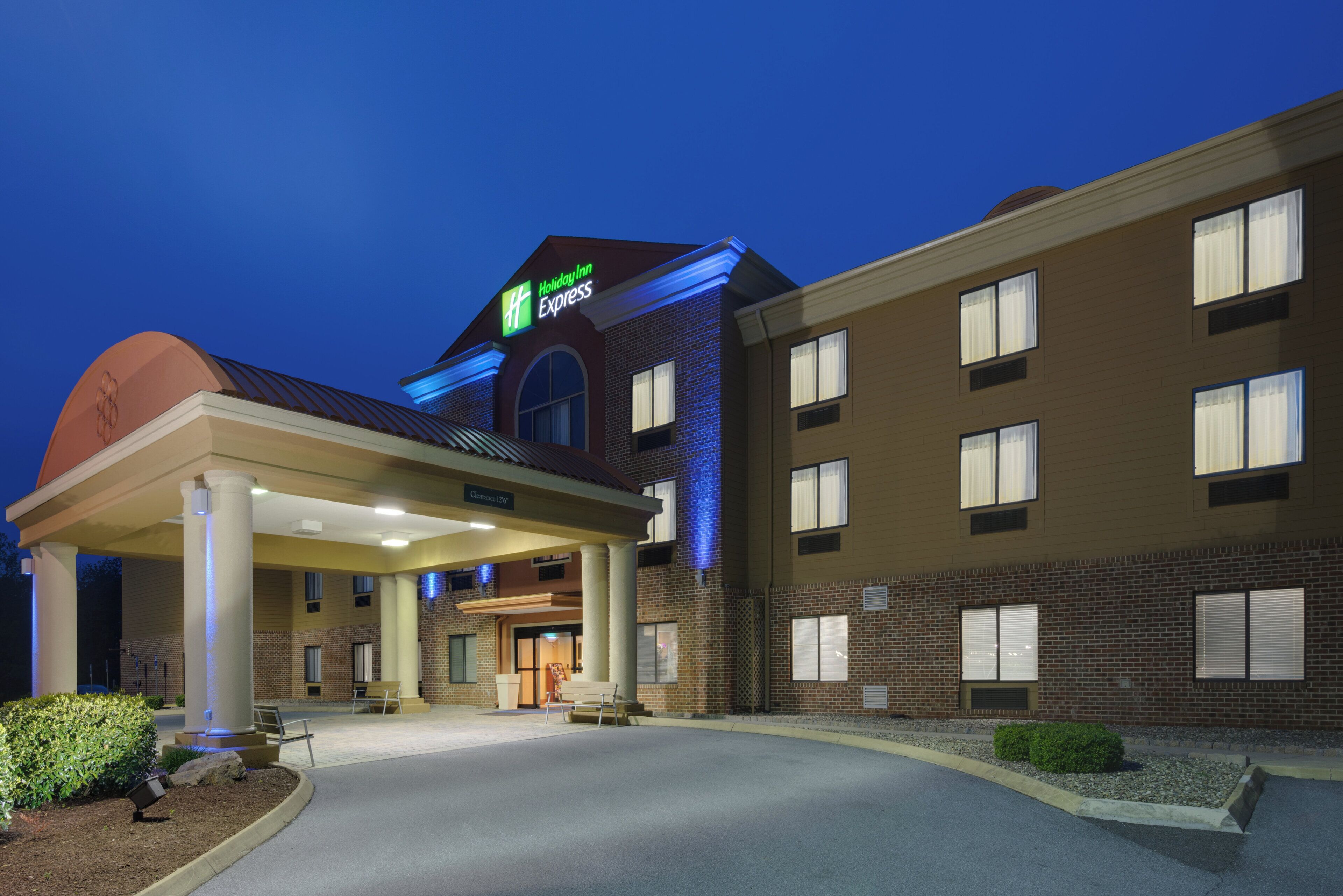 A Holiday Inn Express building with a covered entrance, brick facade, and a clear sky.