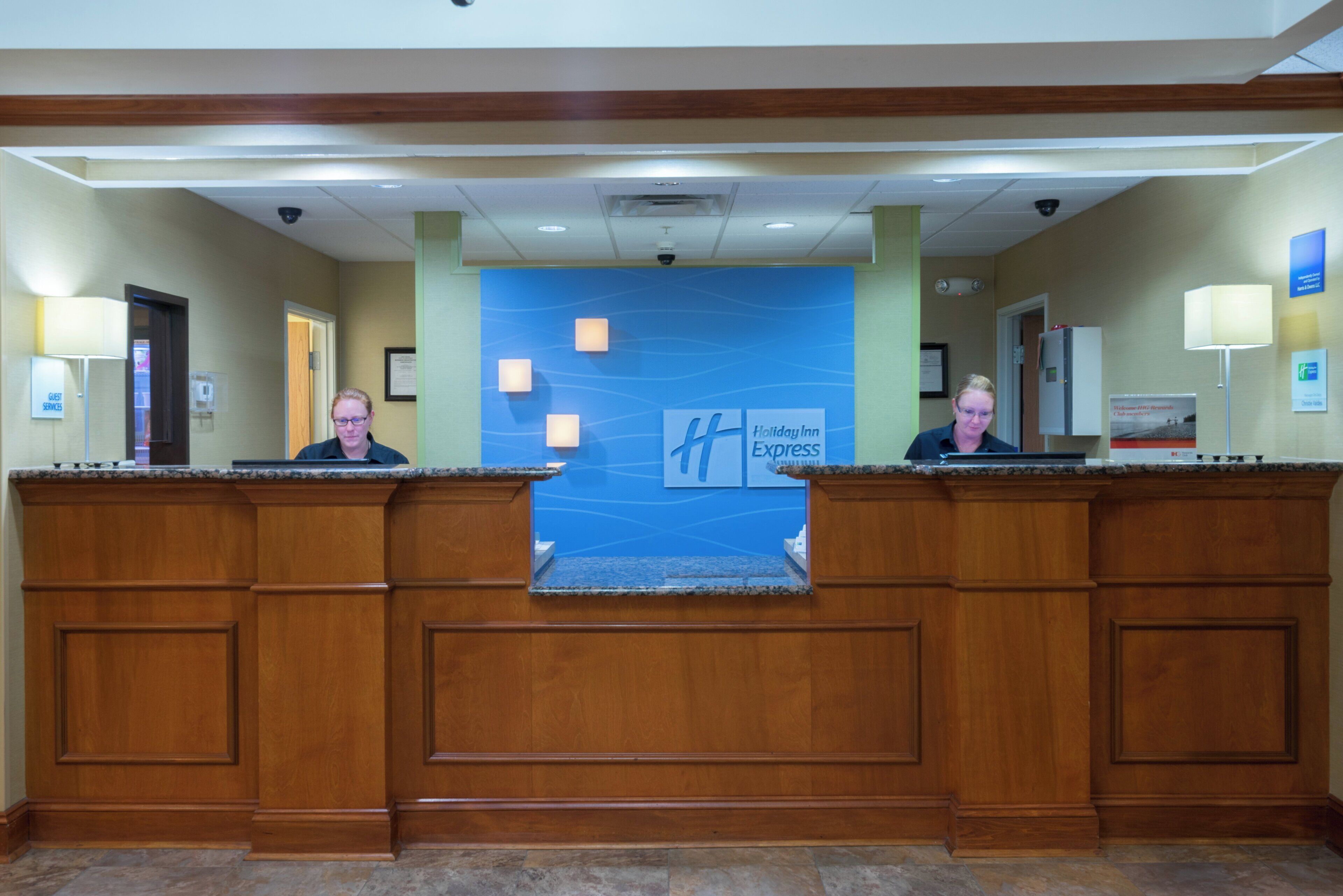 A hotel reception desk with a blue wall featuring the Holiday Inn Express logo.