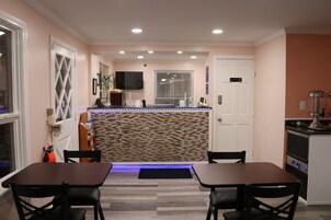 Un comedor con una isla central, una zona de cocina con estufa y una puerta que da a otra habitación.