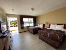 Habitación de hotel con dos camas, televisión, escritorio y ventana con cortinas.