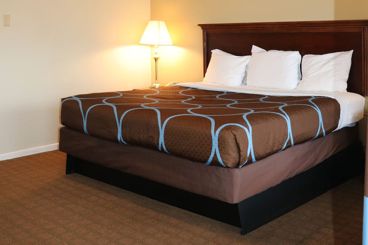 A hotel room with a bed, a nightstand, a lamp, and a ceiling light.