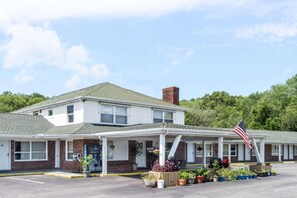A motel with a covered front porch, a brick facade, and an American flag. - Elite Inn (Moosup)