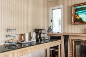 Una cocina con papel tapiz a rayas, una estación de café, una chimenea y una ventana con vistas.
