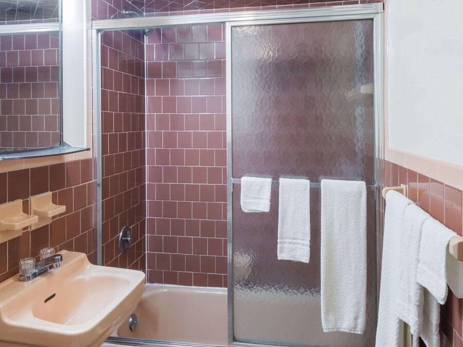 A bathroom with a sink, mirror, and shower area.