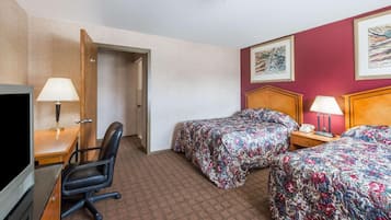 Habitación de hotel con dos camas, un escritorio con silla, un televisor y una puerta que da a otra habitación.