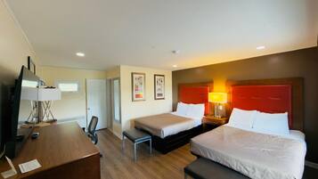 Habitación de hotel con dos camas, un escritorio, una silla y un televisor.