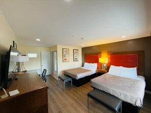 A hotel room with two beds, a desk, a chair, and a TV. - Elite Inn (Moosup)