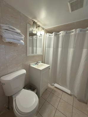 Un baño con inodoro, lavabo, espejo y cortina de ducha.