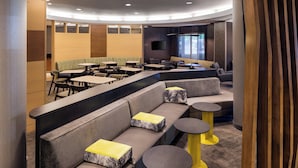 A modern lounge area with seating arrangements, tables, and a flat-screen TV mounted on the wall. - SpringHill Suites by Marriott Bakersfield (Bakersfield)