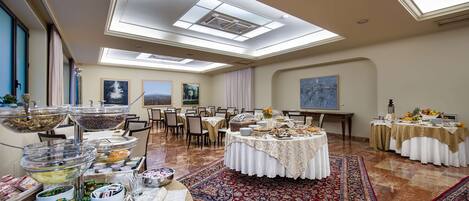Un amplio salón de banquetes con techos altos, tragaluces y una mesa redonda central con mantel blanco.