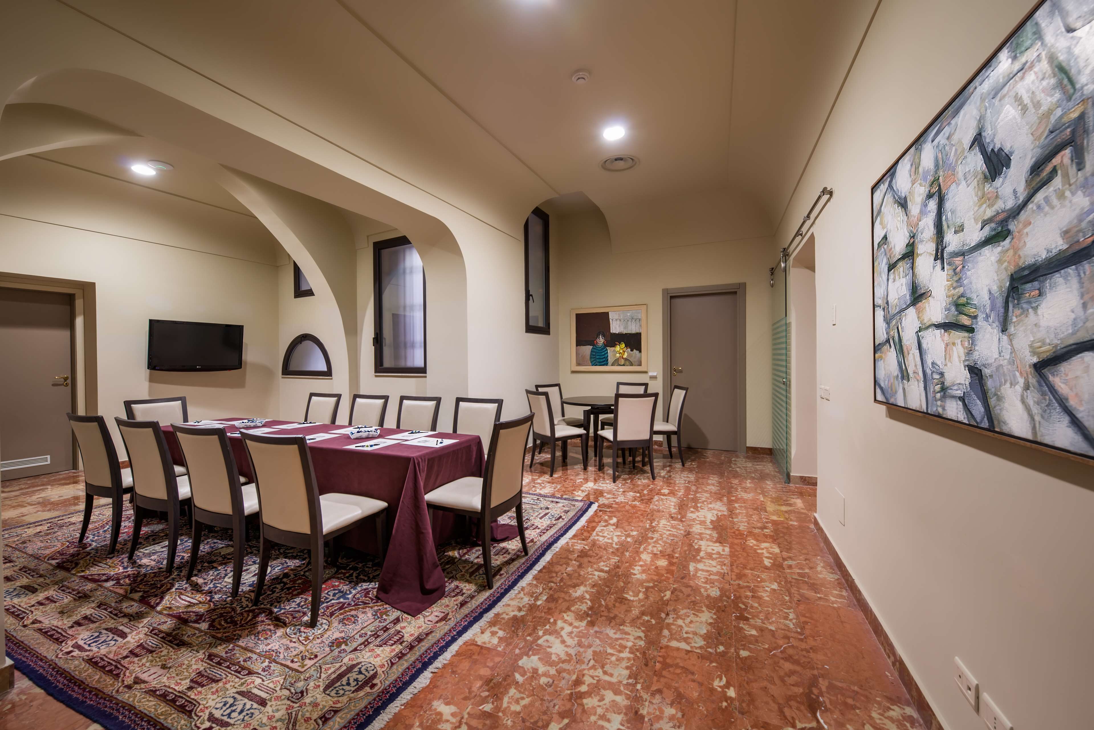 A conference room with a long table, chairs, a patterned carpet, and a large abstract painting on the wall.