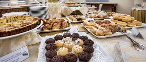 Un bufé con diversos productos horneados, incluyendo pasteles, muffins y repostería.