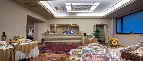 A hotel dining area with a high ceiling, skylight, and a buffet setup.