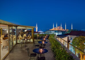 A rooftop terrace with tables and chairs, overlooking a historic building with multiple minarets. - Tan Hotel - Special Class (Istanbul)