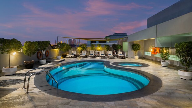 A swimming pool with multiple levels and lounge chairs, surrounded by potted plants and a modern building.