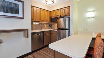 Una cocina moderna con electrodomésticos de acero inoxidable, armarios de madera y encimera blanca.