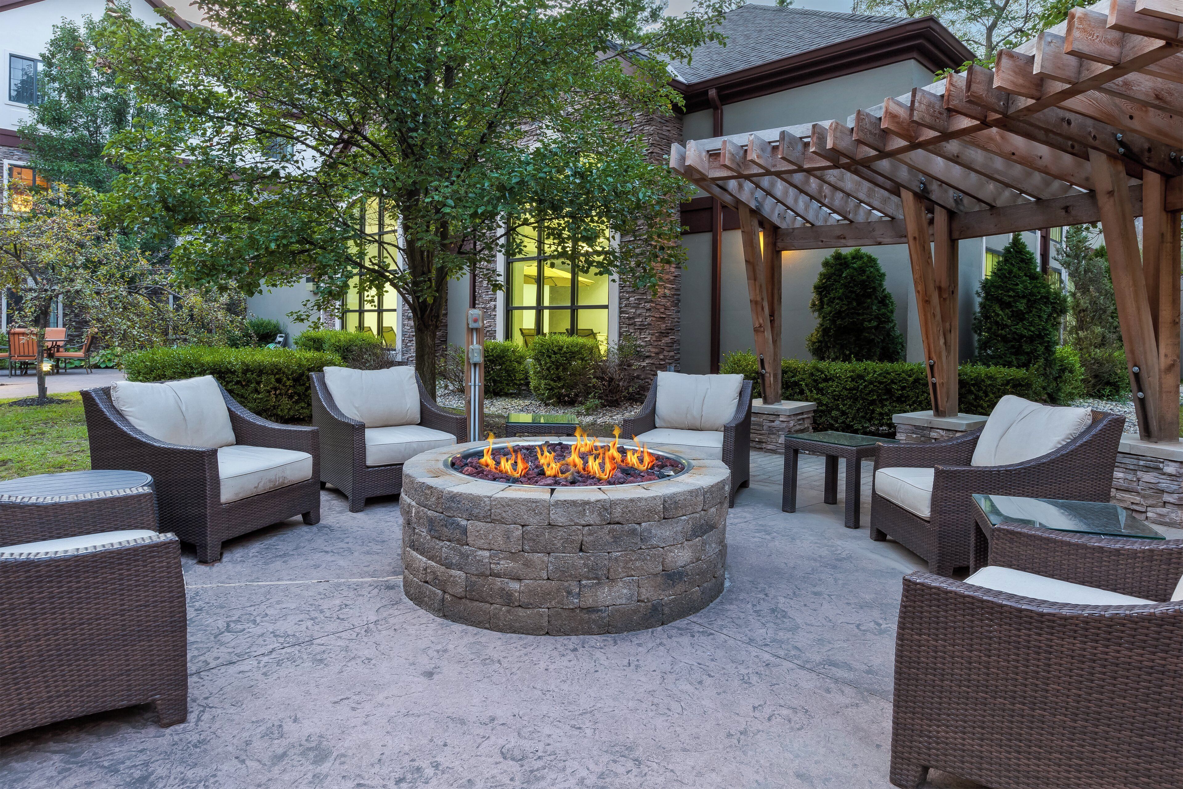 An outdoor seating area with wicker furniture and a stone fire pit.