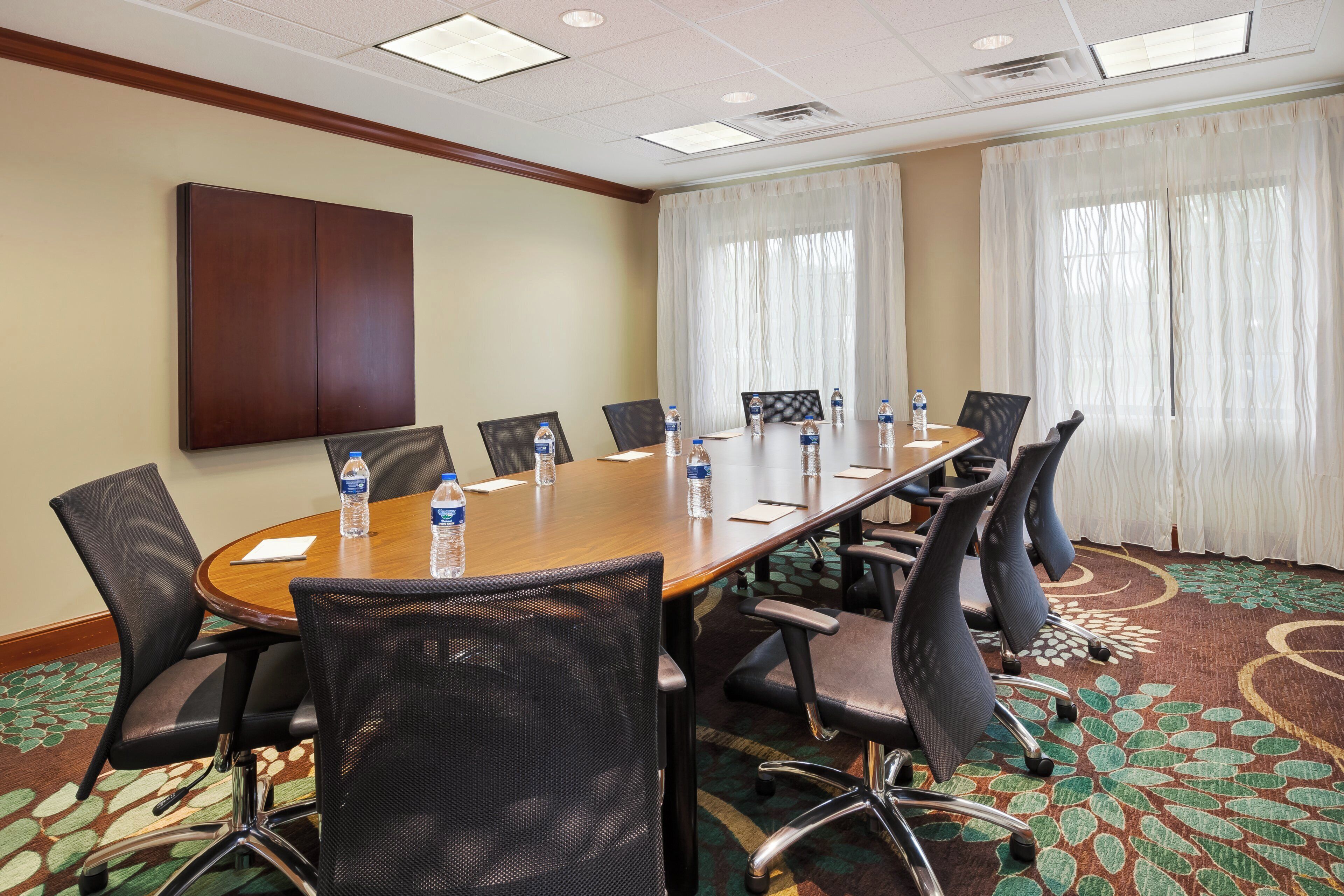 A conference room with a long table, chairs, water bottles, and a large cabinet.