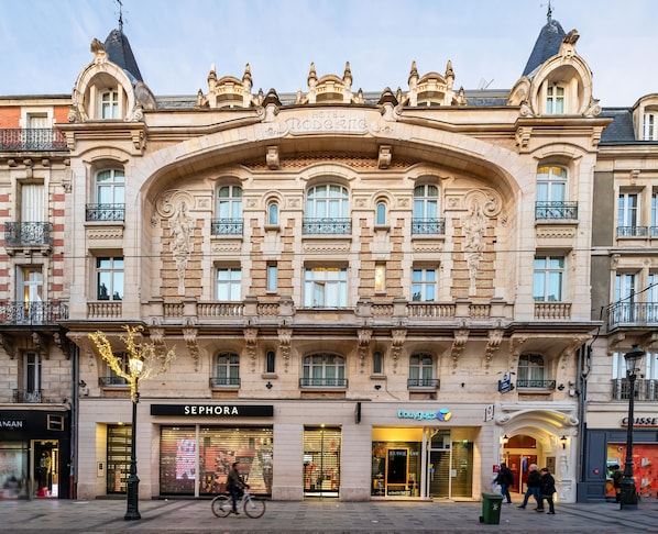 A historic building with ornate architecture, featuring a prominent arched entrance and multiple balconies.