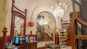 A reception area with a wooden desk, a chandelier, and a mirror.