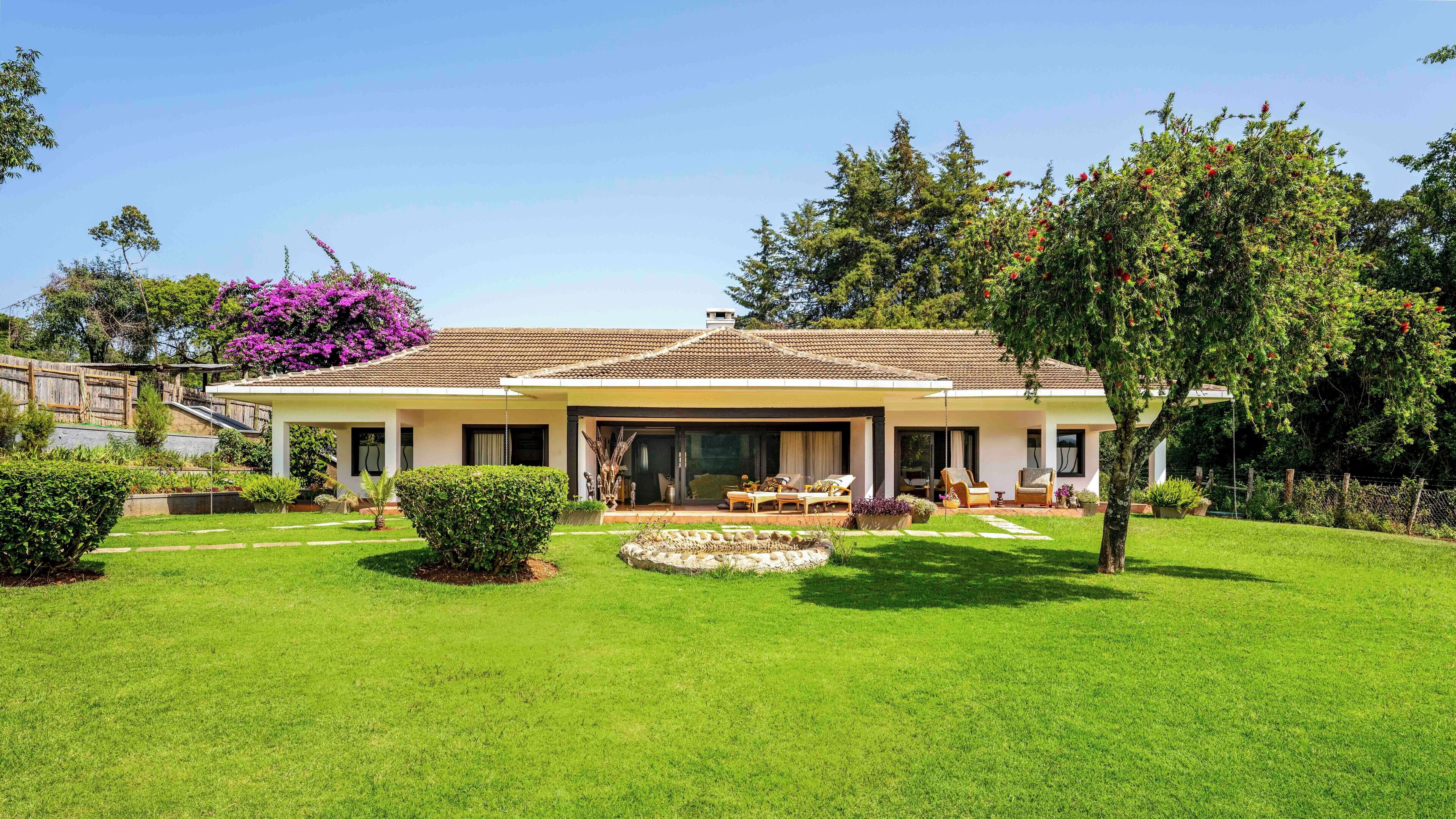 A two-story house with a patio, a lawn, and a garden.
