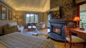 A cozy room with a fireplace, a bed, a desk, and a chair. - Fairmont Mount Kenya Safari (Nanyuki)