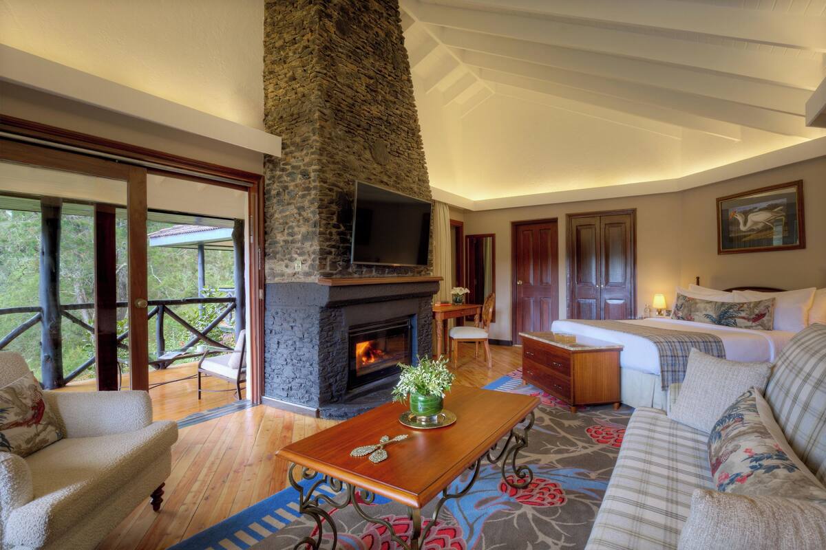 A spacious living area with a stone fireplace, a sofa, a coffee table, and a television mounted on the wall.