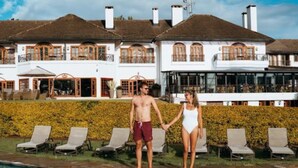 A poolside view of a hotel with a large pool, lounge chairs, and a well-maintained hedge. - Fairmont Mount Kenya Safari (Nanyuki)