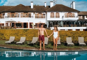 Stunning two-story building with a traditional facade, surrounded by a well-manicured hedge and a serene pool area.