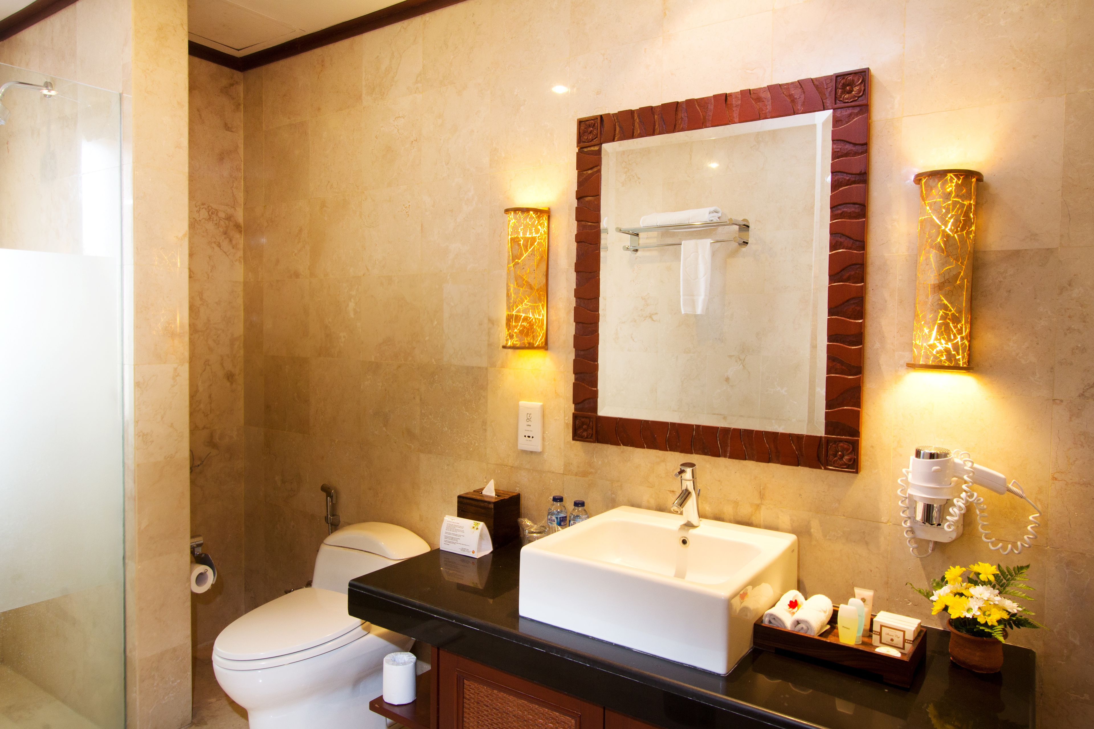Un baño moderno con pared de mármol, un lavamanos grande, un inodoro y un box de ducha con paredes de vidrio.
