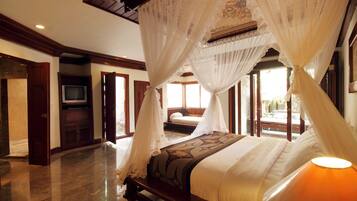 A spacious bedroom with a large bed, a television, and a view of the outdoors.