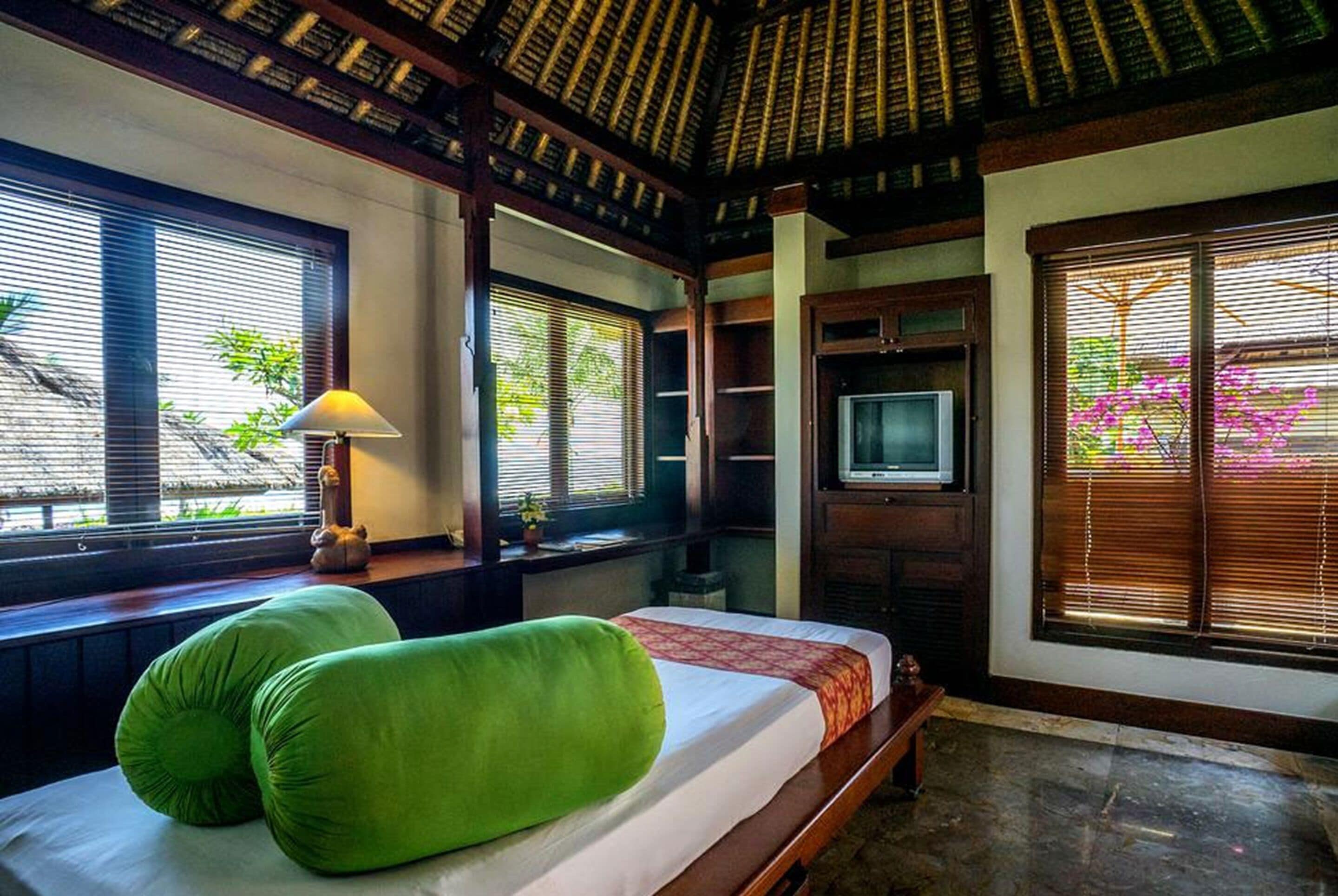 Una habitación con una cama, televisión y ventana con persianas.