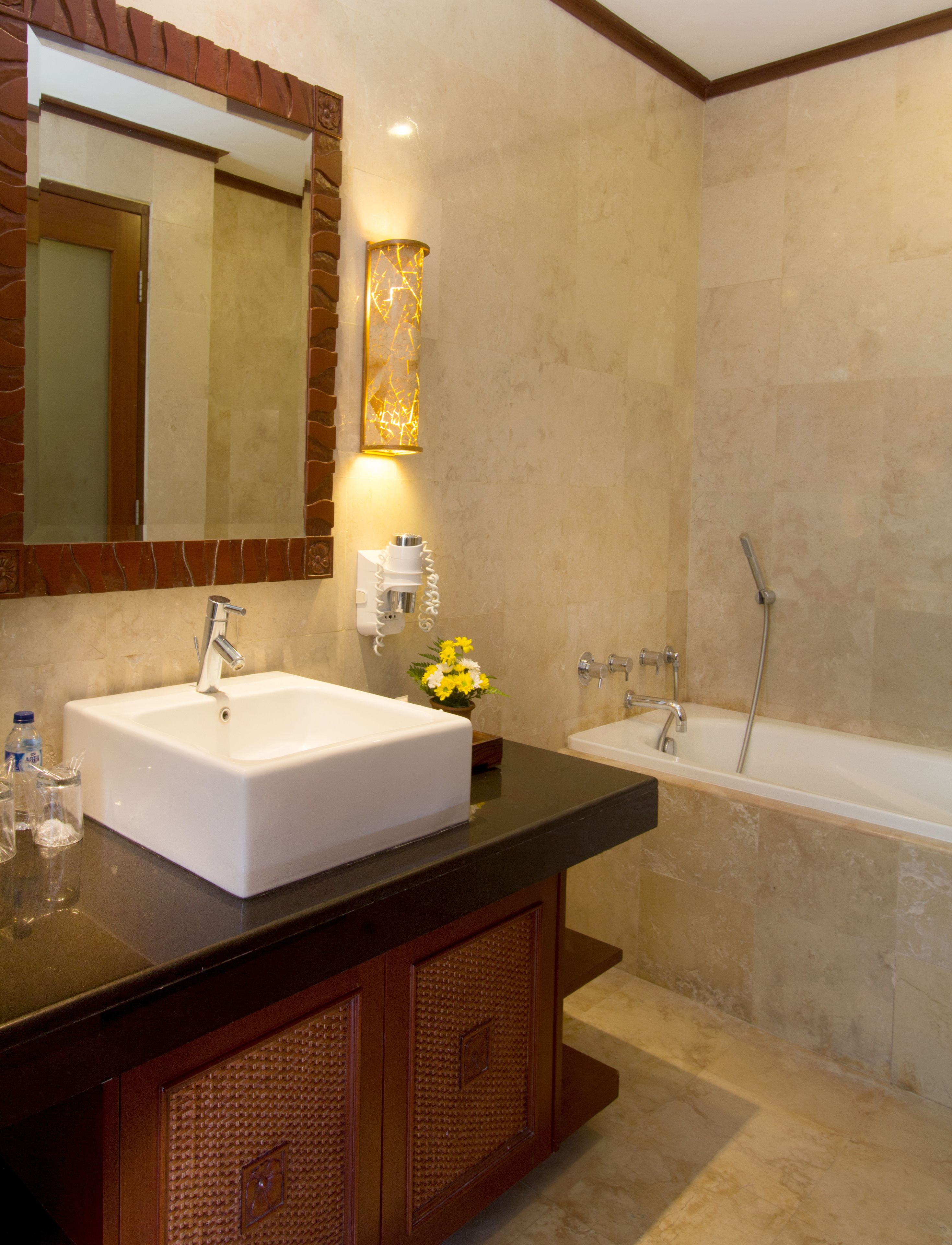 Un baño moderno con un lavabo grande de color blanco, un espejo, una lámpara empotrada en la pared y una bañera.