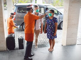 Un grupo de personas siendo revisadas en la entrada de un aeropuerto.