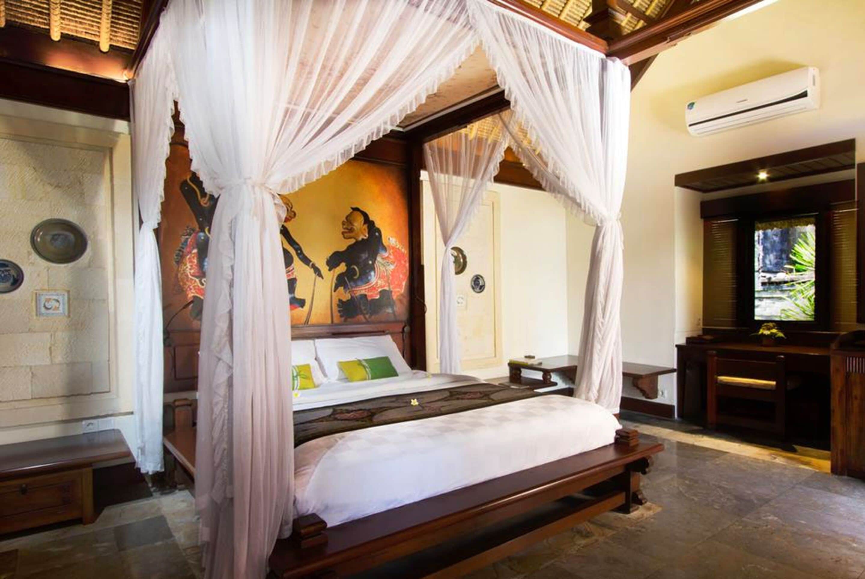 A four-poster bed with a canopy, a television, and a wall with a mural.