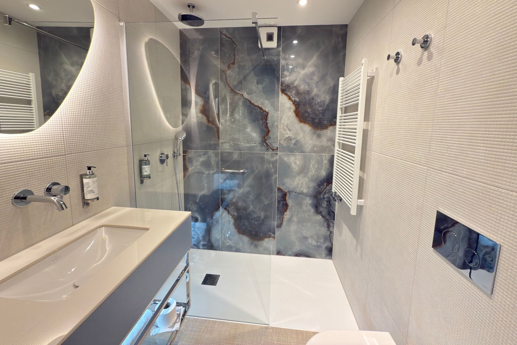A modern bathroom with a large bathtub, a shower with a glass enclosure, and a marble backsplash.