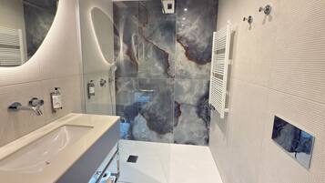 A modern bathroom with a large bathtub, a shower with a glass enclosure, and a marble backsplash.