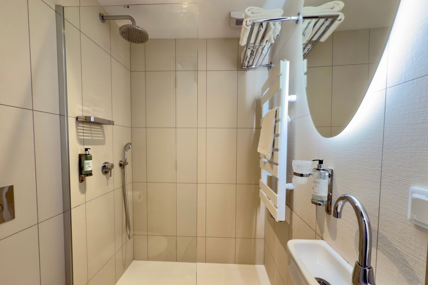 Une salle de bain moderne avec une douche à parois de verre, un lavabo blanc et un porte-serviettes.