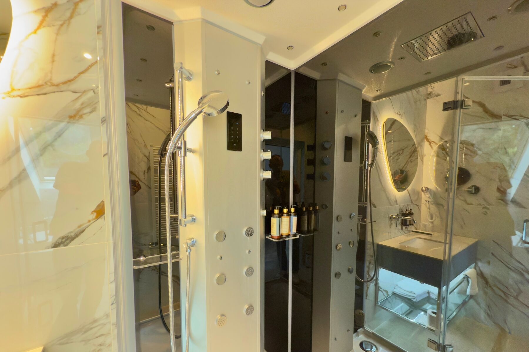 Un baño moderno con ducha de vidrio, tocador con espejo y paredes de mármol.