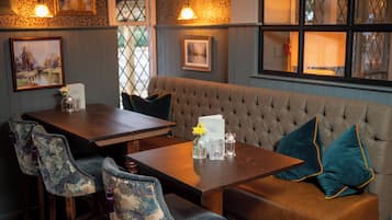 A cozy seating area with a cushioned bench and a wooden table, featuring floral-patterned chairs and a menu sign.