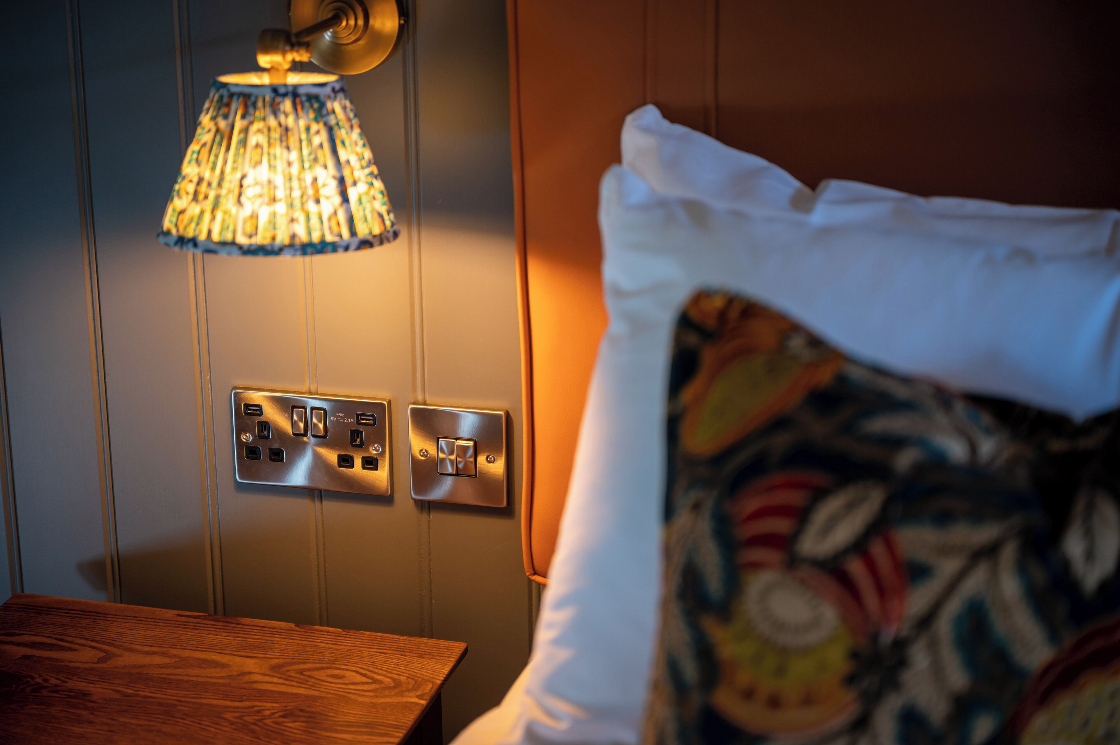 A room with a wooden table, a wall-mounted light fixture, and a power outlet.