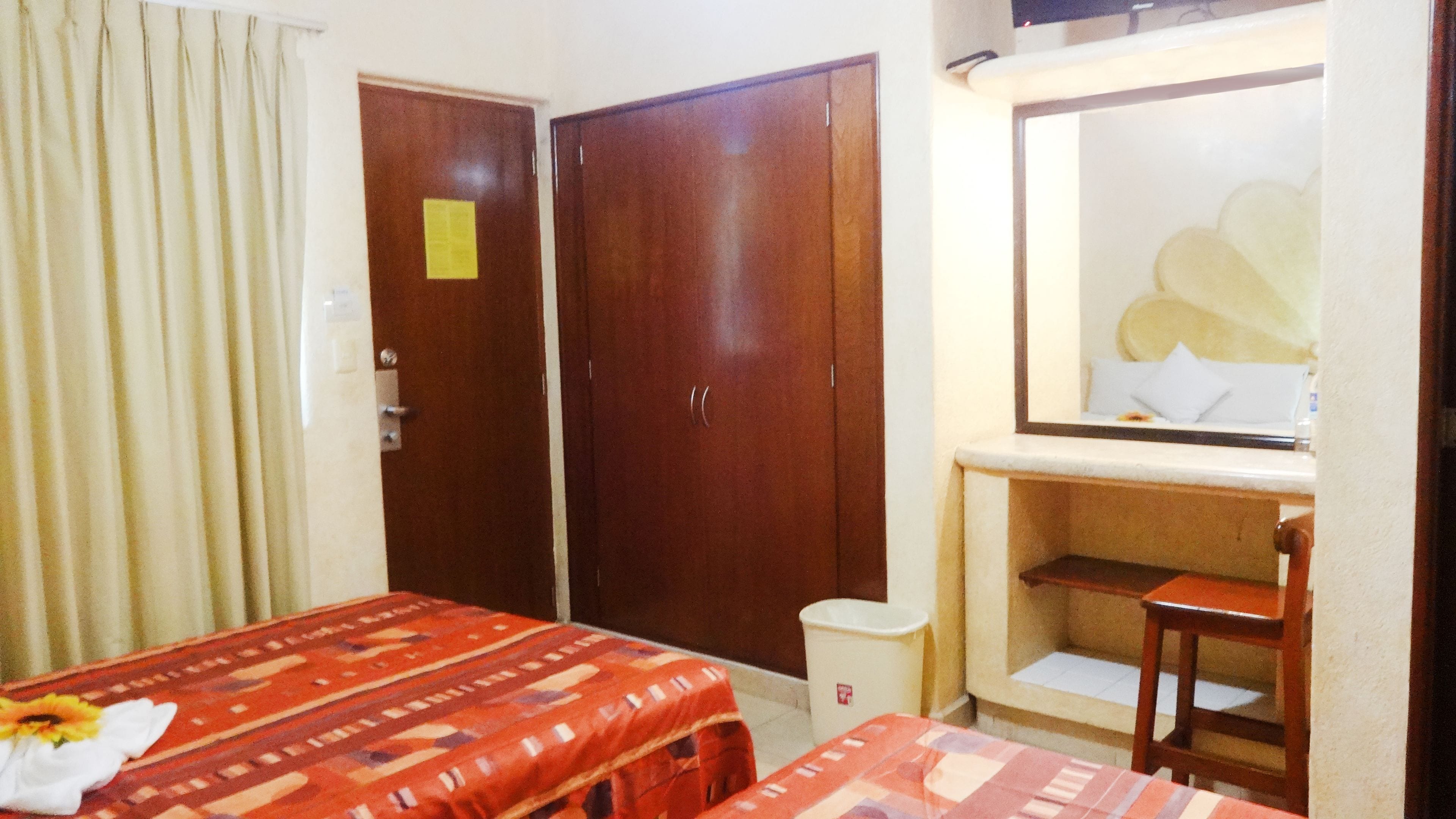 Una habitación de hotel con una cama, un escritorio, un espejo y dos armarios.