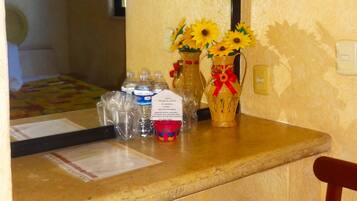 A bathroom with a mirror, a sink, a vase with sunflowers, and toiletries.
