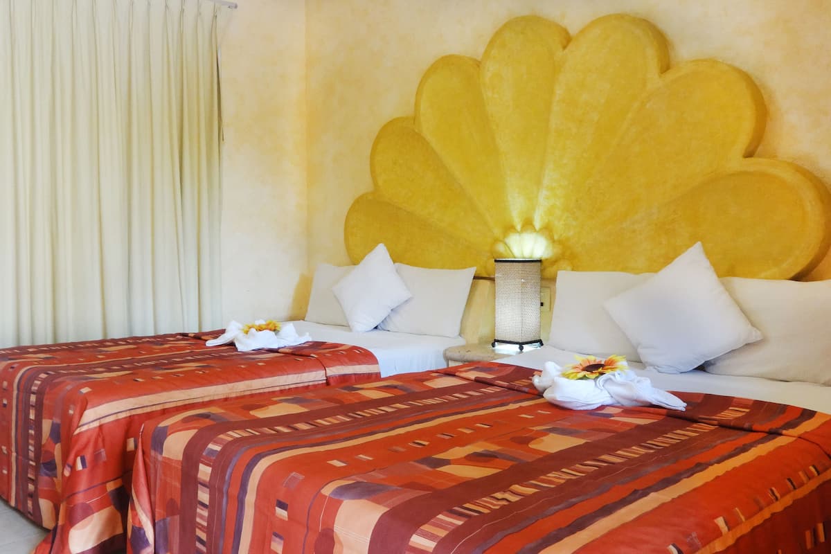 Habitación de hotel con dos camas, un cabecero decorativo grande y una lámpara de noche.