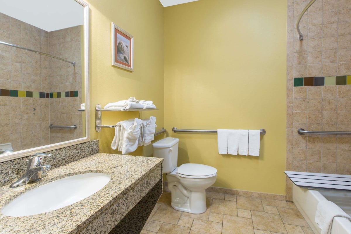 A bathroom with a granite sink, white toilet, and a shower area.