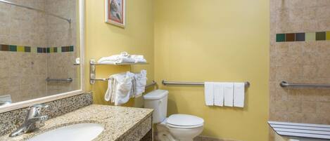 A bathroom with a granite sink, white toilet, and a shower area.
