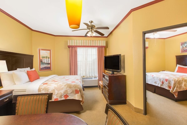 A hotel room with two beds, a television, a desk, and a chair.